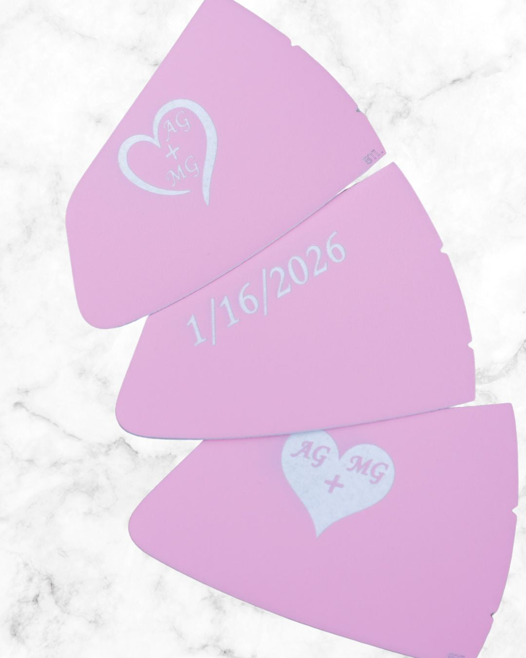 Three purple heart-shaped stencils with personalized text on a marble surface