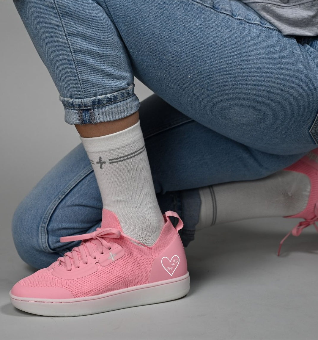 Person wearing pink sneakers with a heart design on a gray background